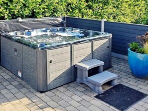 A hot tub with a wooden exterior, a small step, and a potted plant nearby. - 5 Star Holiday Home in Vinderup (Vinderup)