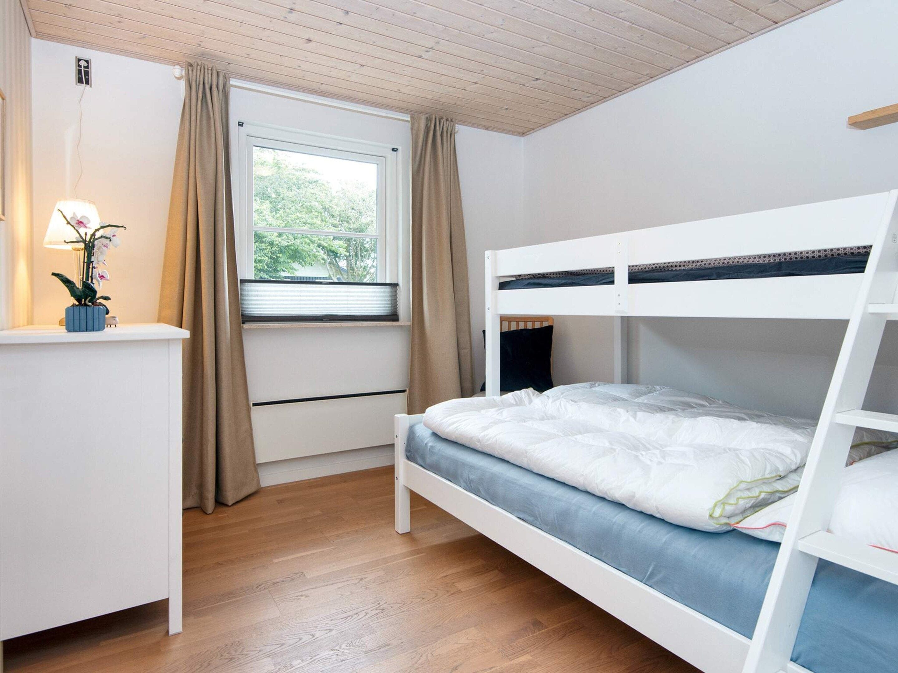 Un lit superposé avec un bureau et une fenêtre avec des rideaux.