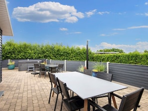 An outdoor patio with a table and chairs, surrounded by a low wall and greenery. - 5 Star Holiday Home in Vinderup (Vinderup)