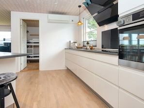 Una cocina moderna con horno empotrado, una lámpara colgante y un ventanal que proporciona luz natural.