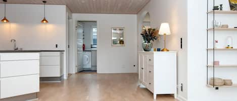 A modern kitchen with a wooden ceiling, white cabinetry, and pendant lighting.