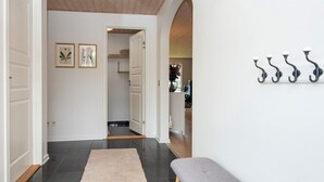 A hallway with a bench, a coat rack, and framed artwork on the wall.