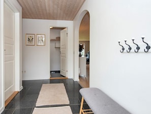 A hallway with a bench, a coat rack, and framed artwork on the wall. - 5 Star Holiday Home in Vinderup (Vinderup)