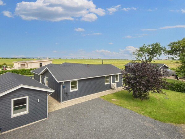 A residential area with houses, a gravel driveway, and a grassy field in the background. - 5 Star Holiday Home in Vinderup (Vinderup)