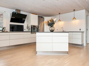 A modern kitchen with a central island, stainless steel appliances, and pendant lighting.