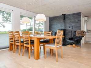 A modern dining area with a wooden table and chairs, pendant lights, and a view of the outdoors. - 5 Star Holiday Home in Vinderup (Vinderup)