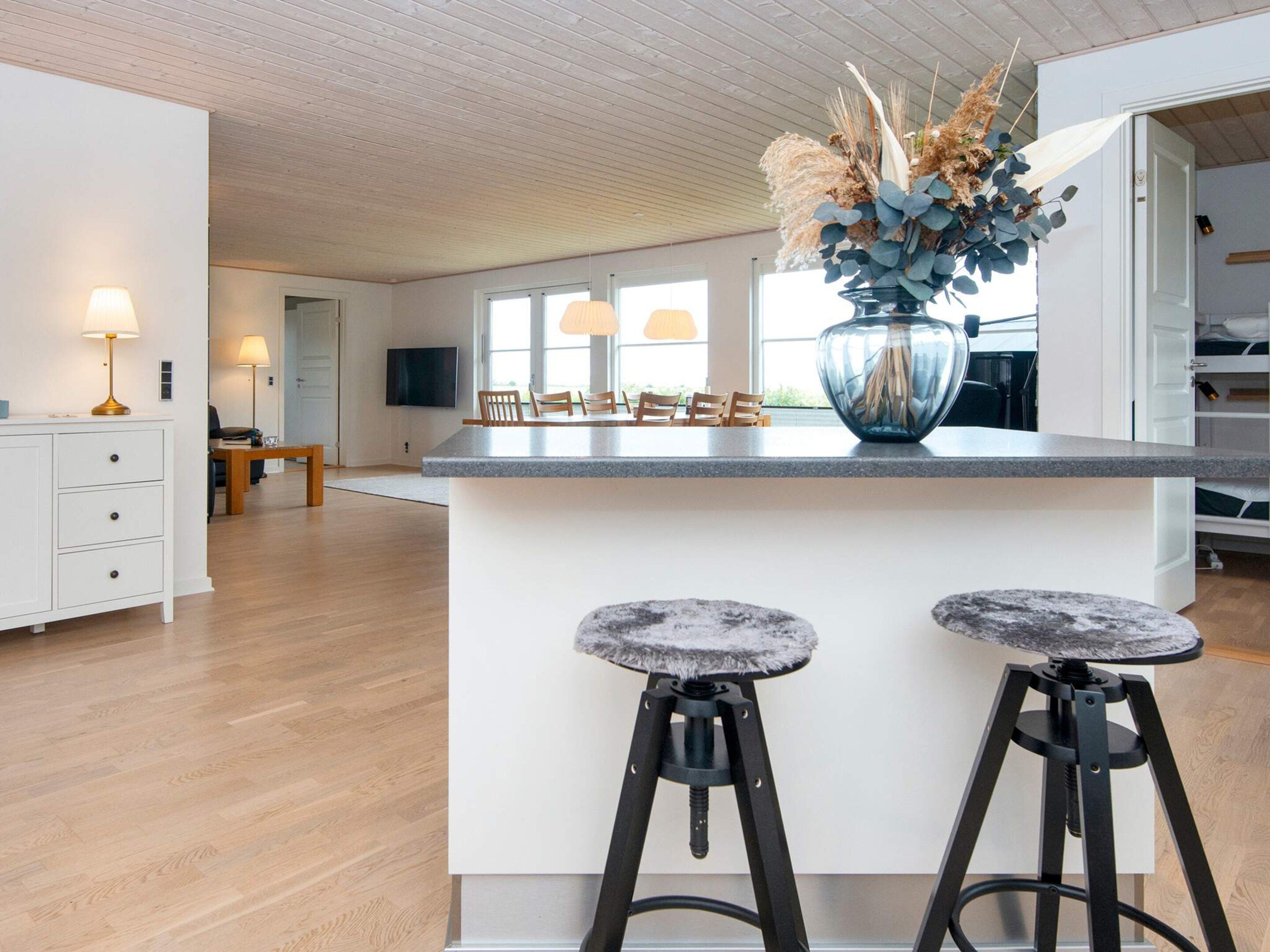 A modern kitchen with a central island, bar stools, and a decorative vase.