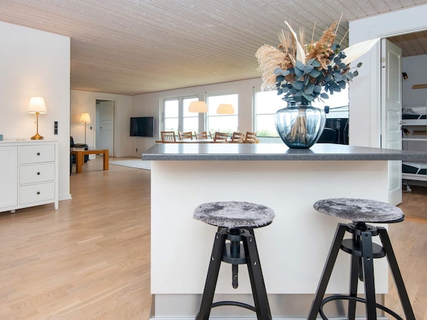 A modern kitchen with a central island, bar stools, and a decorative vase.