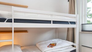 A bunk bed with a window view, a radiator, and a curtain.