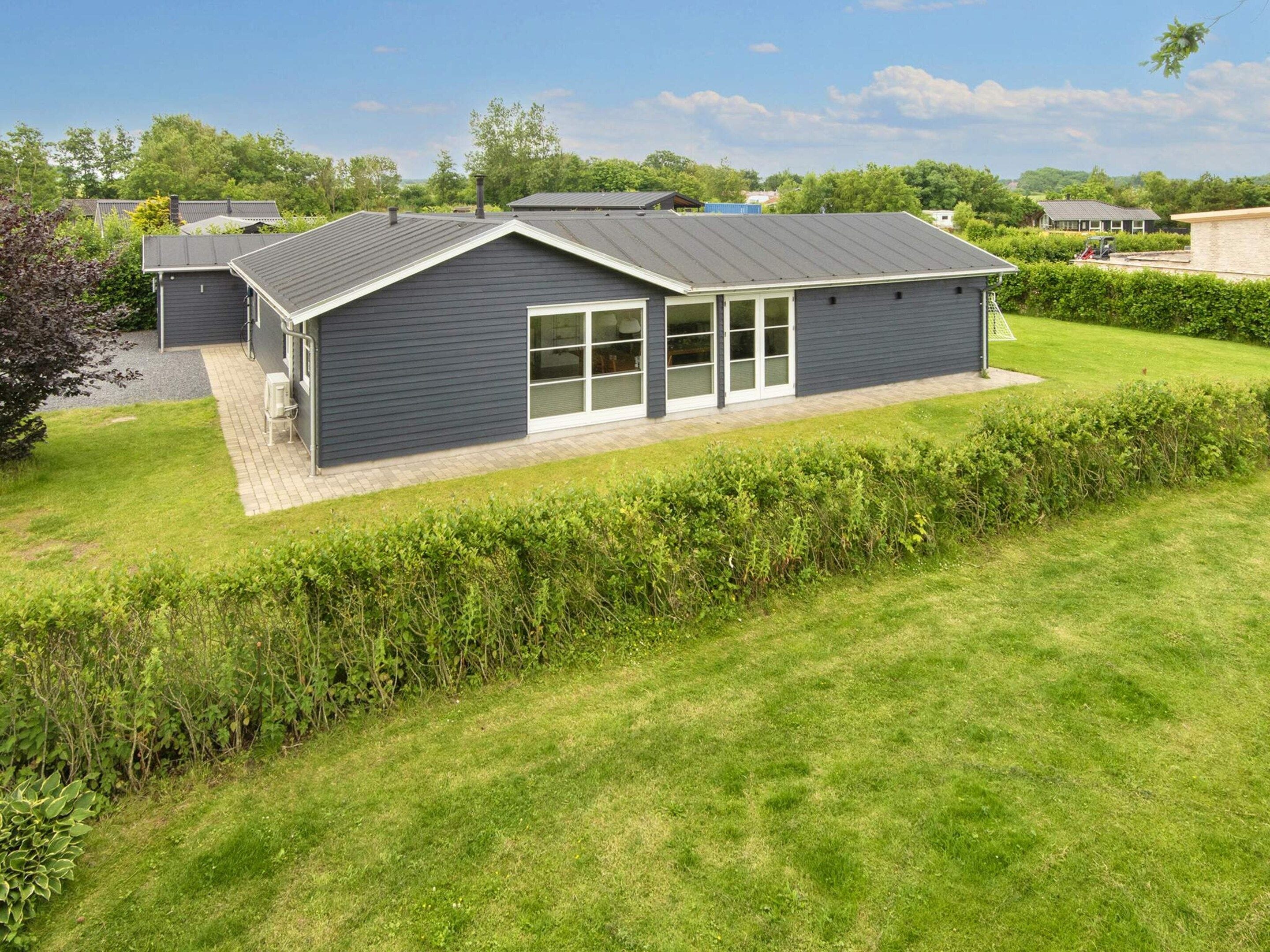 A modern building with a flat roof, large windows, and a well-maintained lawn.