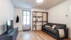 A modern living room with a grey sofa, a flat-screen TV, and a wooden floor. - Marinetti Suite 8 (Como)