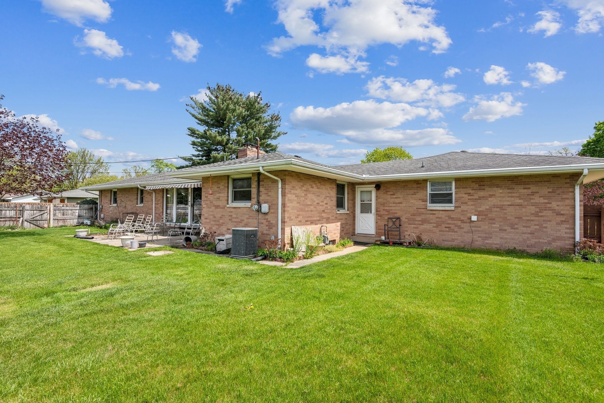 A two-story brick house with a well-maintained lawn and outdoor seating area.