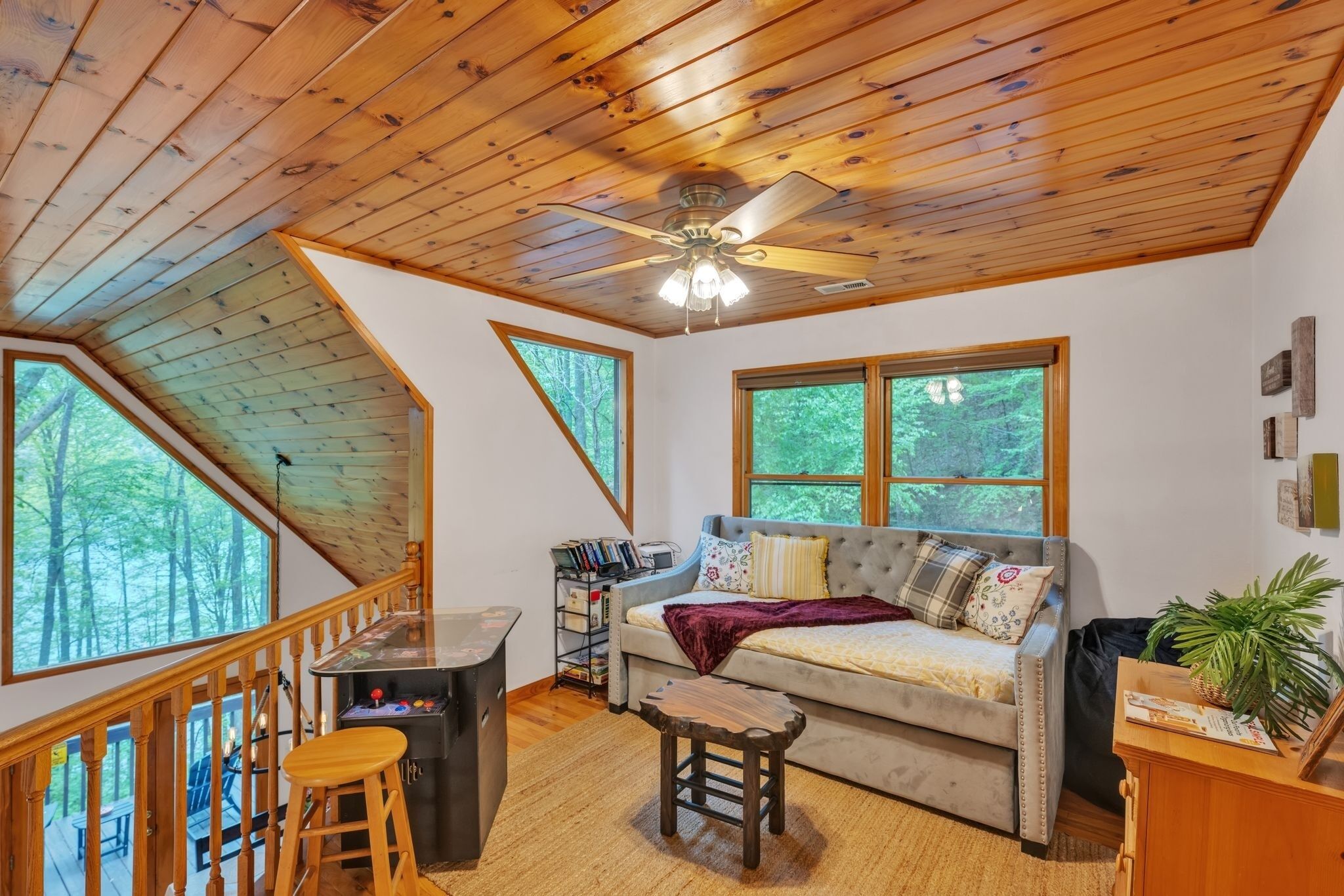 A cozy room with a wooden ceiling, a sofa with cushions, a small table, and a bookshelf.
