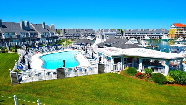 A hotel with a swimming pool, a covered deck, and a view of the marina. - Harbour Island 306l 2 Bedroom Condo by RedAwning (Ocean City)