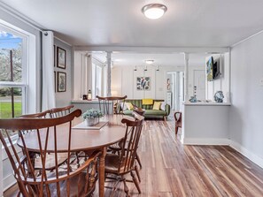 Relax in this open-plan living space with a dining area featuring a round table and matching chairs.