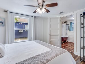 Relax in this serene bedroom with a large bed, ceiling fan, and sliding glass door leading to an outdoor area.