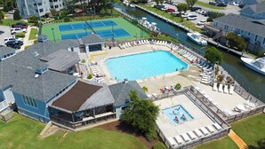 Propiedad residencial con piscina, canchas de tenis y un muelle a orillas de un canal.