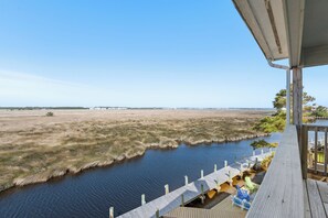 Une terrasse en bois donnant sur une rivière, avec vue sur une côte lointaine.