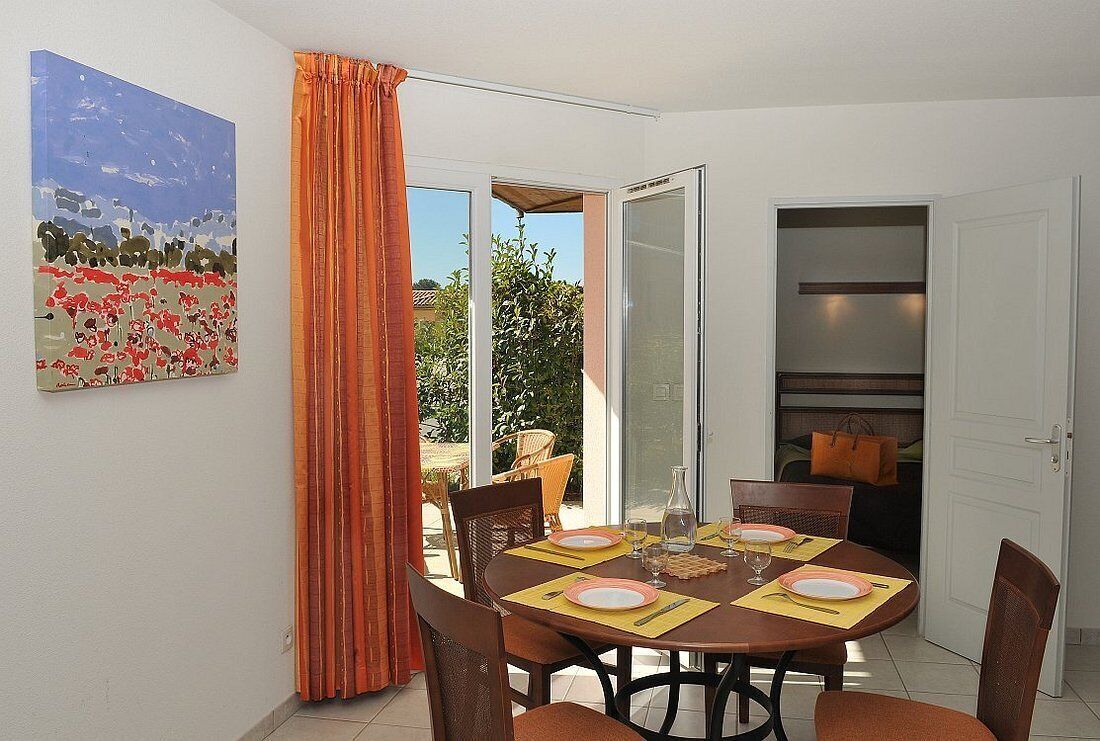A dining area with a table set for four, chairs, a painting on the wall, and a sliding glass door leading to an outdoor area.