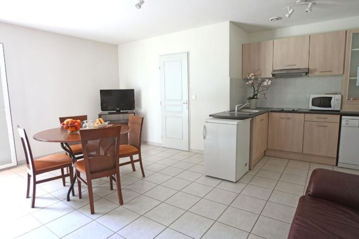 A compact living space with a dining area, kitchenette, and a television.