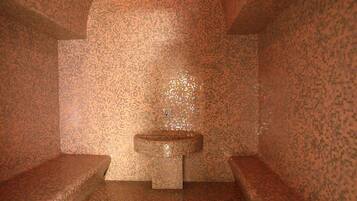 Unique mosaic design adorns the walls, floor, and sink area, complemented by curved benches and a central sink with a square mirror.