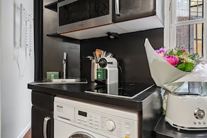 Une cuisine compacte équipée d’un lave-linge, d’une machine à café et d’un grille-pain.