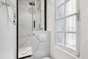 Une salle de bain avec une douche, une fenêtre et un mur en marbre.