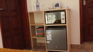 Uma cozinha compacta com micro-ondas e geladeira, prateleiras de madeira e uma porta.
