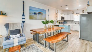 A modern kitchen with white cabinets, a stainless steel refrigerator, and a wooden dining table with benches. - Serene Surfside Beach Retreat w/ Ocean Views! (Freeport)