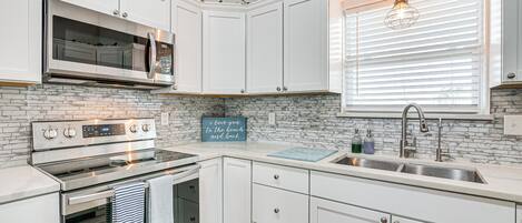 A modern kitchen with white cabinetry, a stainless steel oven, and a built-in microwave.