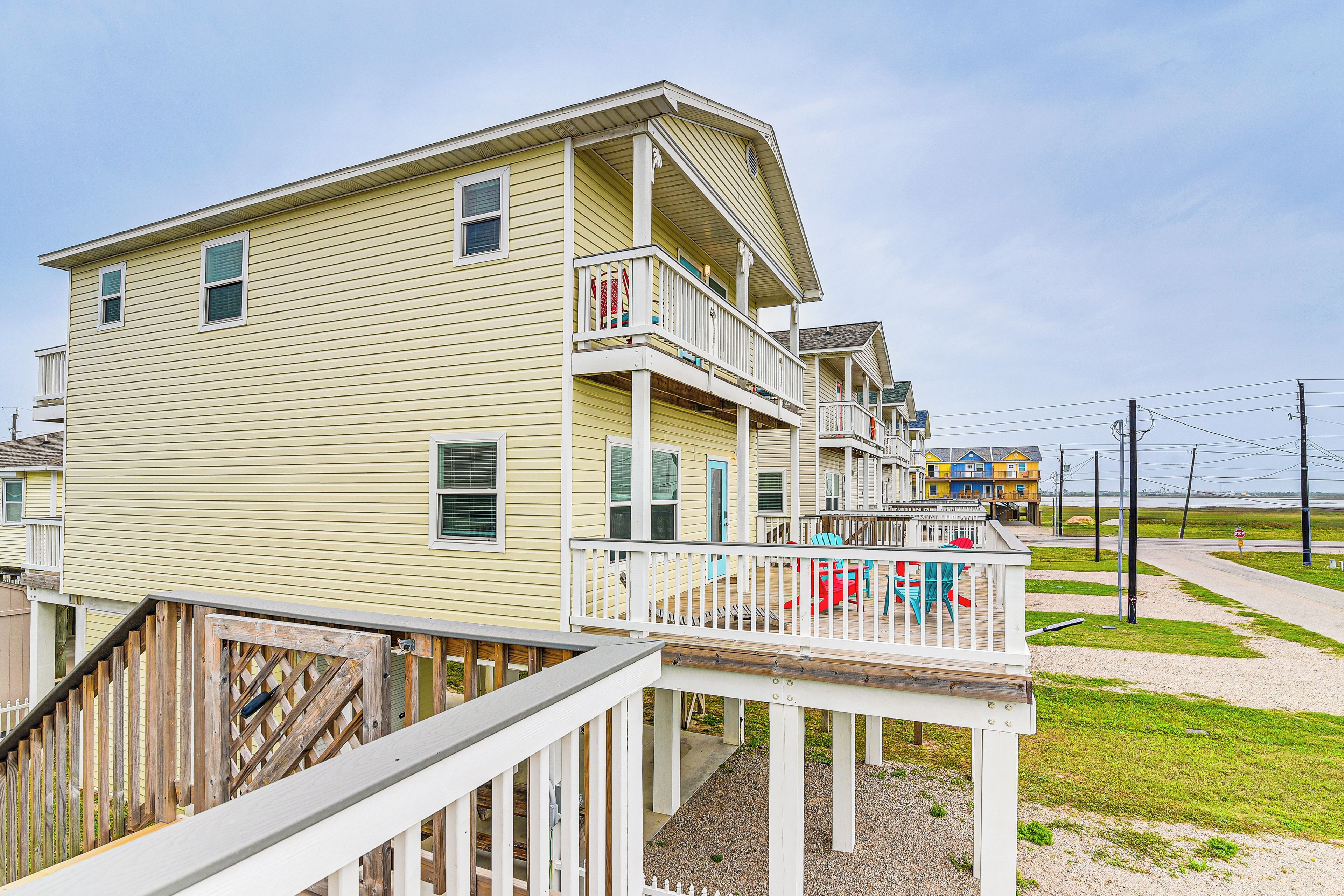 A multi-story building with a balcony, a wooden deck, and a gravel pathway.
