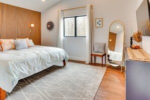 A modern bedroom with a bed, a window, a chair, and a mirror. - Swanton Retreat w/ Game Room, Hot Tub & Trails! (Swanton)