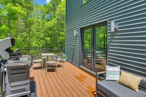 A deck with a grill, outdoor seating, and a sliding glass door leading to a covered area. - Swanton Retreat w/ Game Room, Hot Tub & Trails! (Swanton)