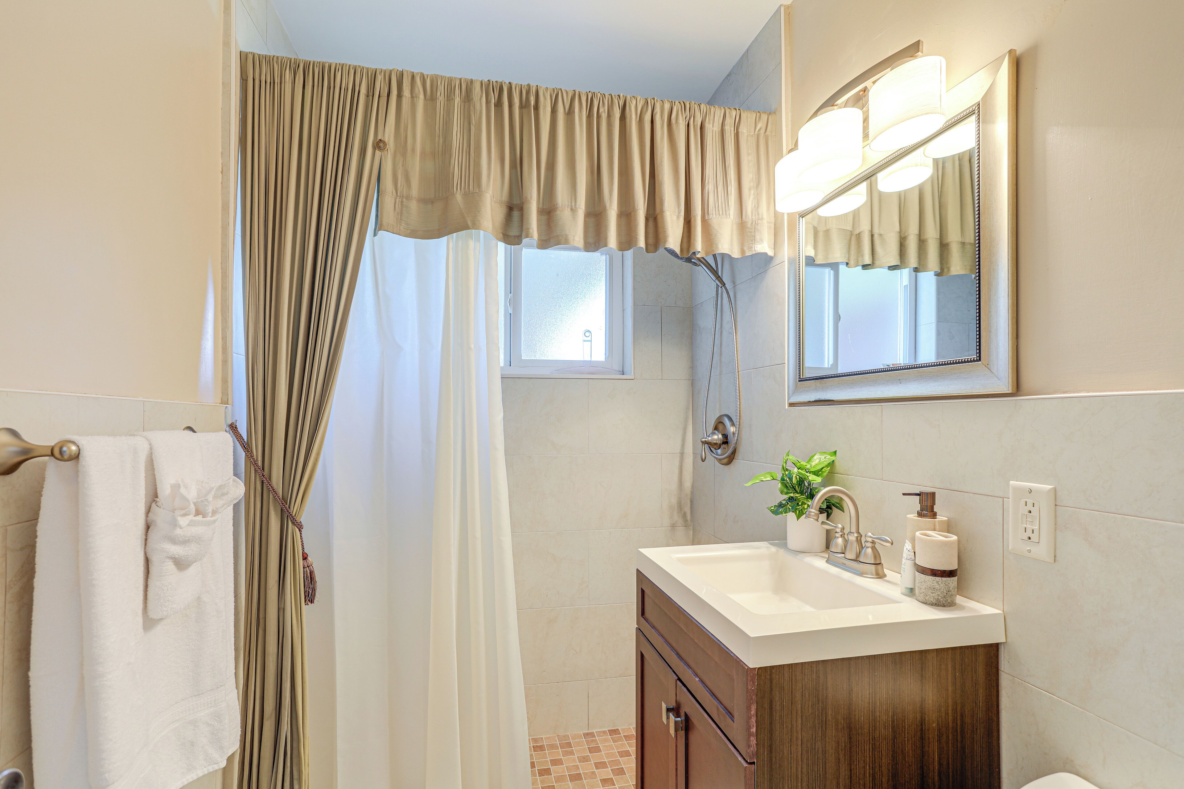 A bathroom with a shower curtain, a sink with a mirror, and a towel rack.