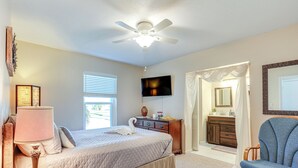 A bedroom with a bed, a nightstand, a chair, a dresser, a television, and a ceiling fan.