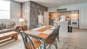 Une cuisine moderne avec des armoires blanches, un four à micro-ondes et une cuisinière. On y trouve également un coin repas avec une table et des chaises en bois.
