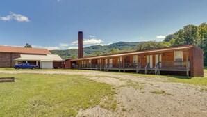 Un motel avec un long couloir bordé de chambres, une cheminée en briques et un camion garé devant.