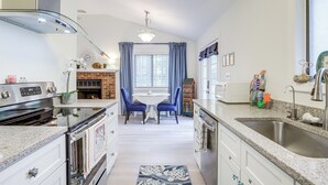 Une cuisine équipée d’une cuisinière, d’un four, d’un évier et d’un coin repas avec des chaises et une table.