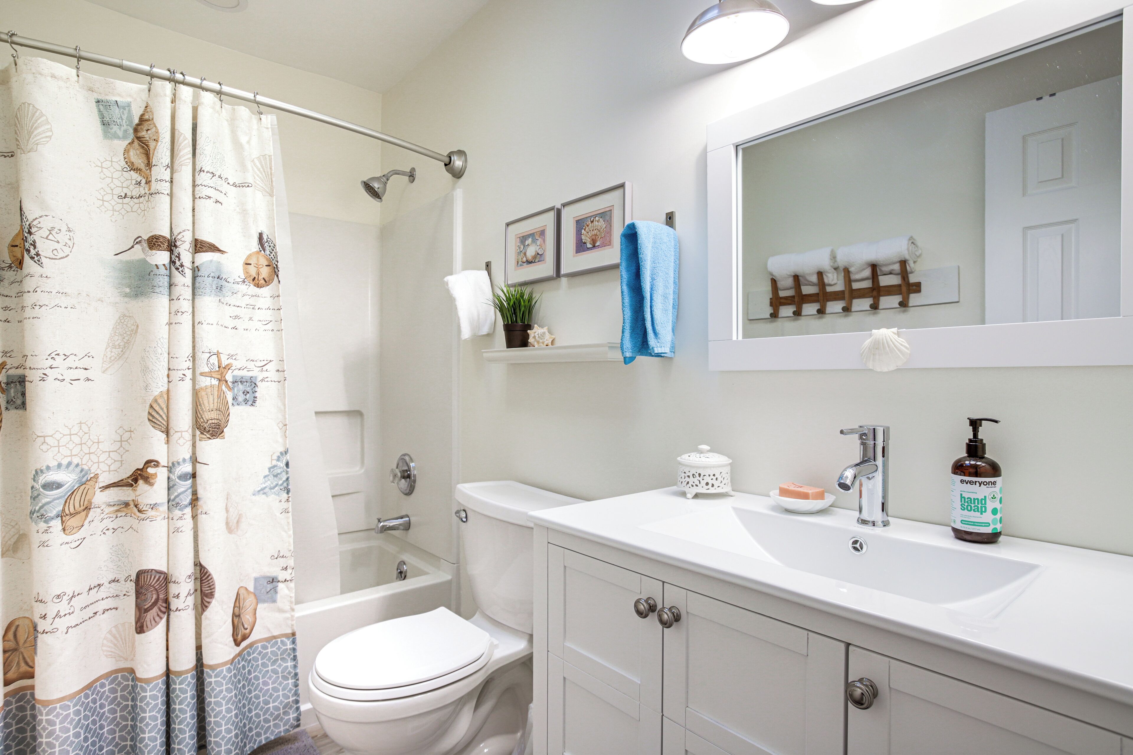 A bathroom with a shower curtain, toilet, sink, and mirror.