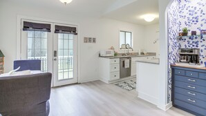 Une cuisine moderne avec des armoires blanches, un four encastré et un four à micro-ondes. On y trouve également un coin repas avec une chaise et une table.
