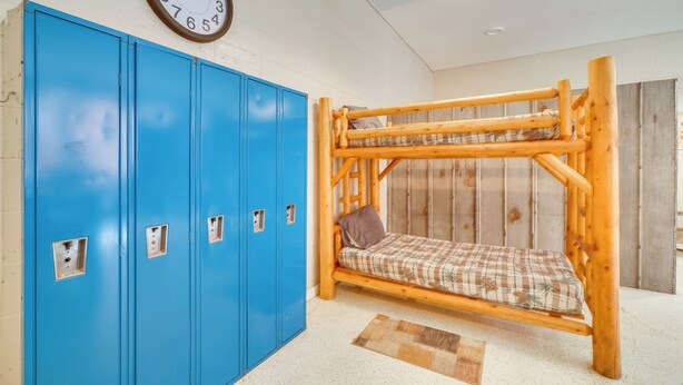 A bunk bed with a plaid mattress, a blue locker room with multiple lockers, and a wall clock. - Riverfront Briceville Apt: Atv, Hike & More! (Briceville)