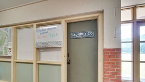 A door with a sign reading "Laundry Co Wash, Dry & Fold" and another sign above it welcoming guests to a mountain retreat. - Riverfront Briceville Apt: Atv, Hike & More! (Briceville)
