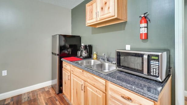 A kitchen with wooden cabinets, a stainless steel refrigerator, a microwave, and a coffee maker. - On-site Hiking & ATV Trails: Briceville Studio (Briceville)