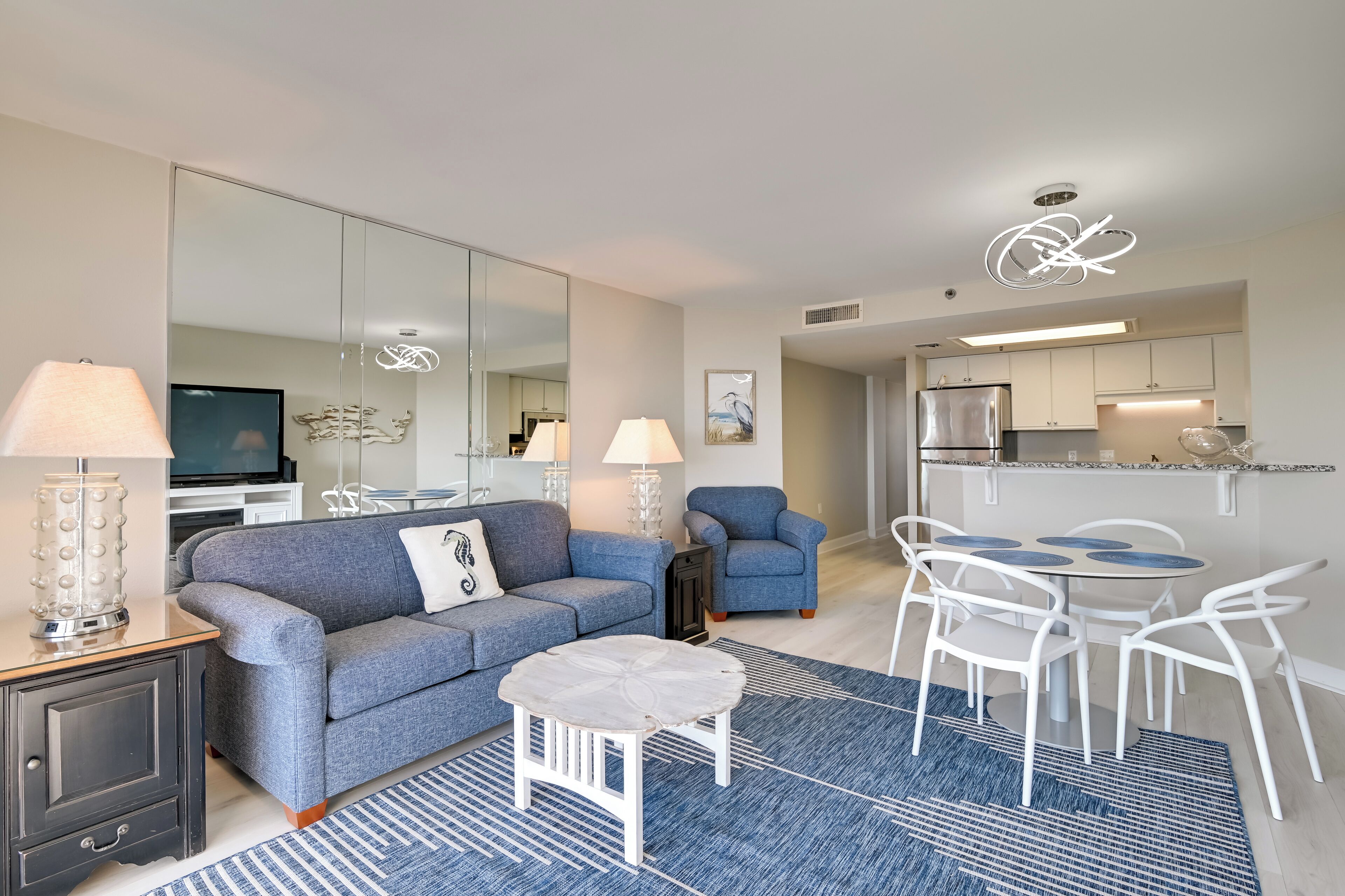 A modern living room with a sofa, a coffee table, and a dining area with chairs and a table.
