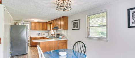 Una cocina compacta con armarios de madera, un refrigerador y una mesa de comedor con sillas.
