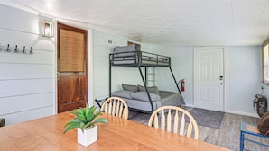 A bunk bed with a gray mattress and pillows, a wooden door, a white wall with hooks, a table with chairs, and a small plant. - Home w/ Bunkroom: 2 Mi to Hatfield & Mccoy Trail (Bluefield)