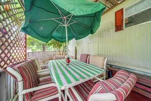 A covered outdoor seating area with a table and chairs, a green umbrella, and a wooden fence. - Andover Home Near State Park w/ Patio & Yard! (Andover)