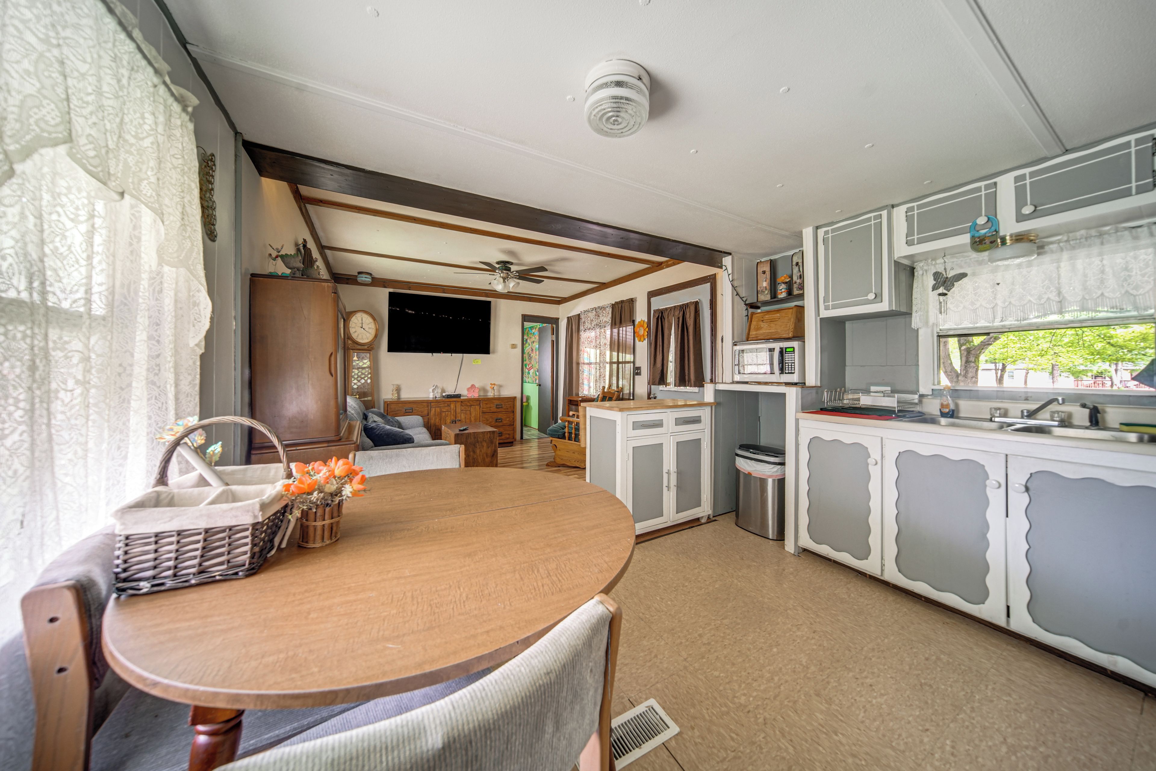A compact kitchen with a dining area, a ceiling fan, and a television mounted on the wall.