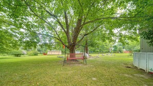 Une cour verdoyante avec une balançoire, un banc et un arbre.