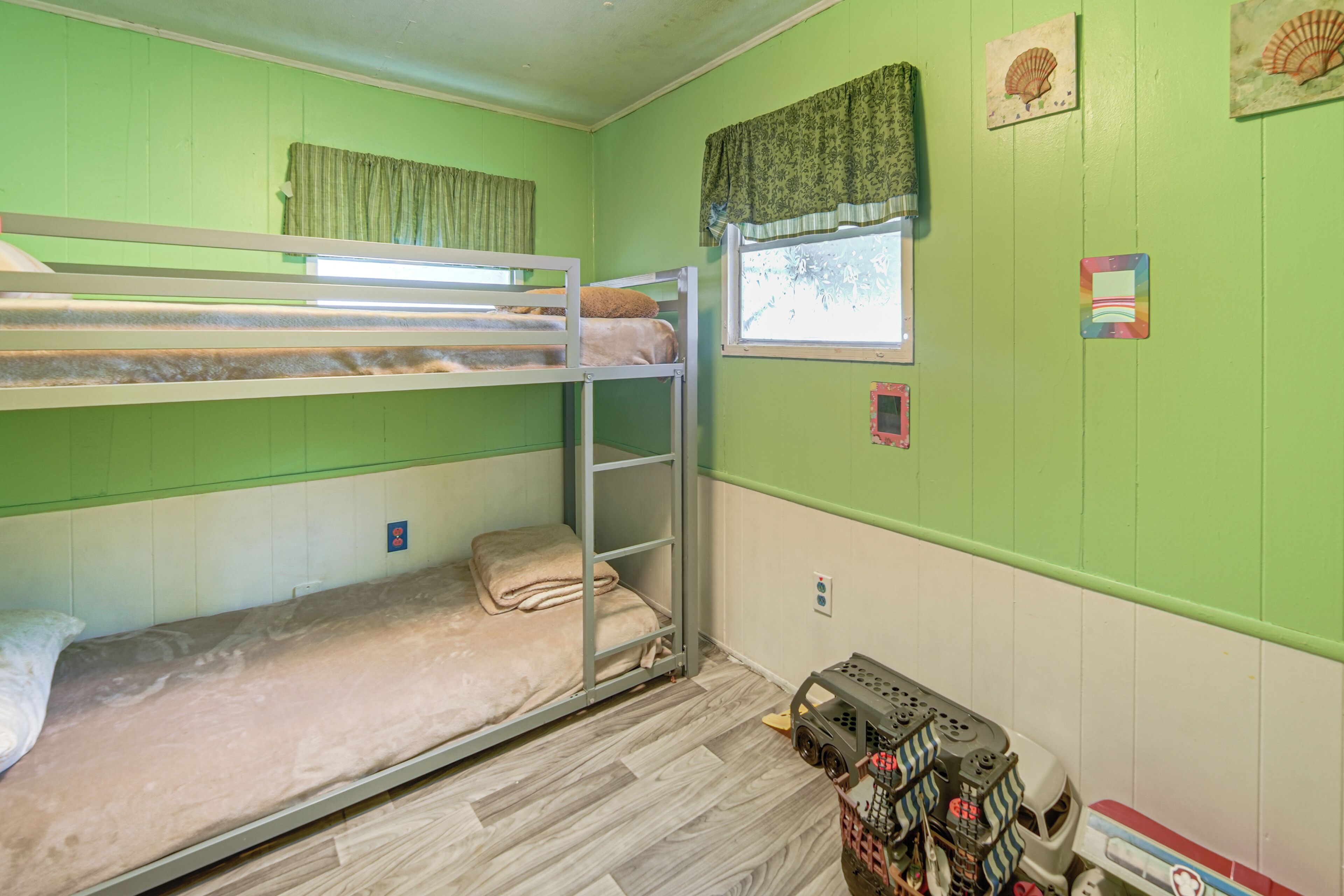 A bunk bed room with a window, a toy car, and a wall with a seashell decoration.